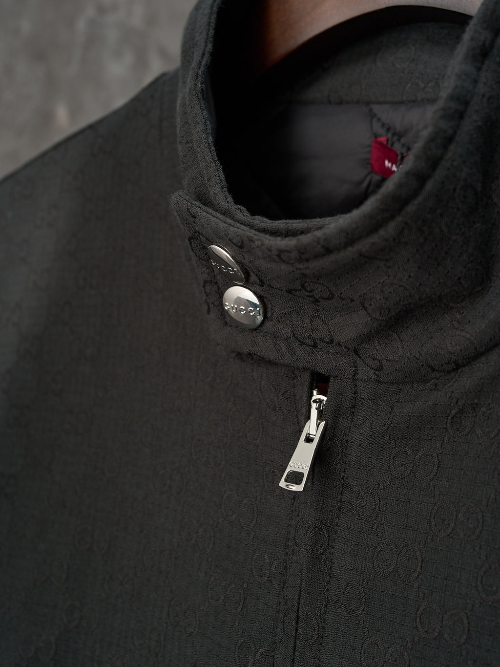 Long jacket collar detail in dark GG pattern with snap button and zipper