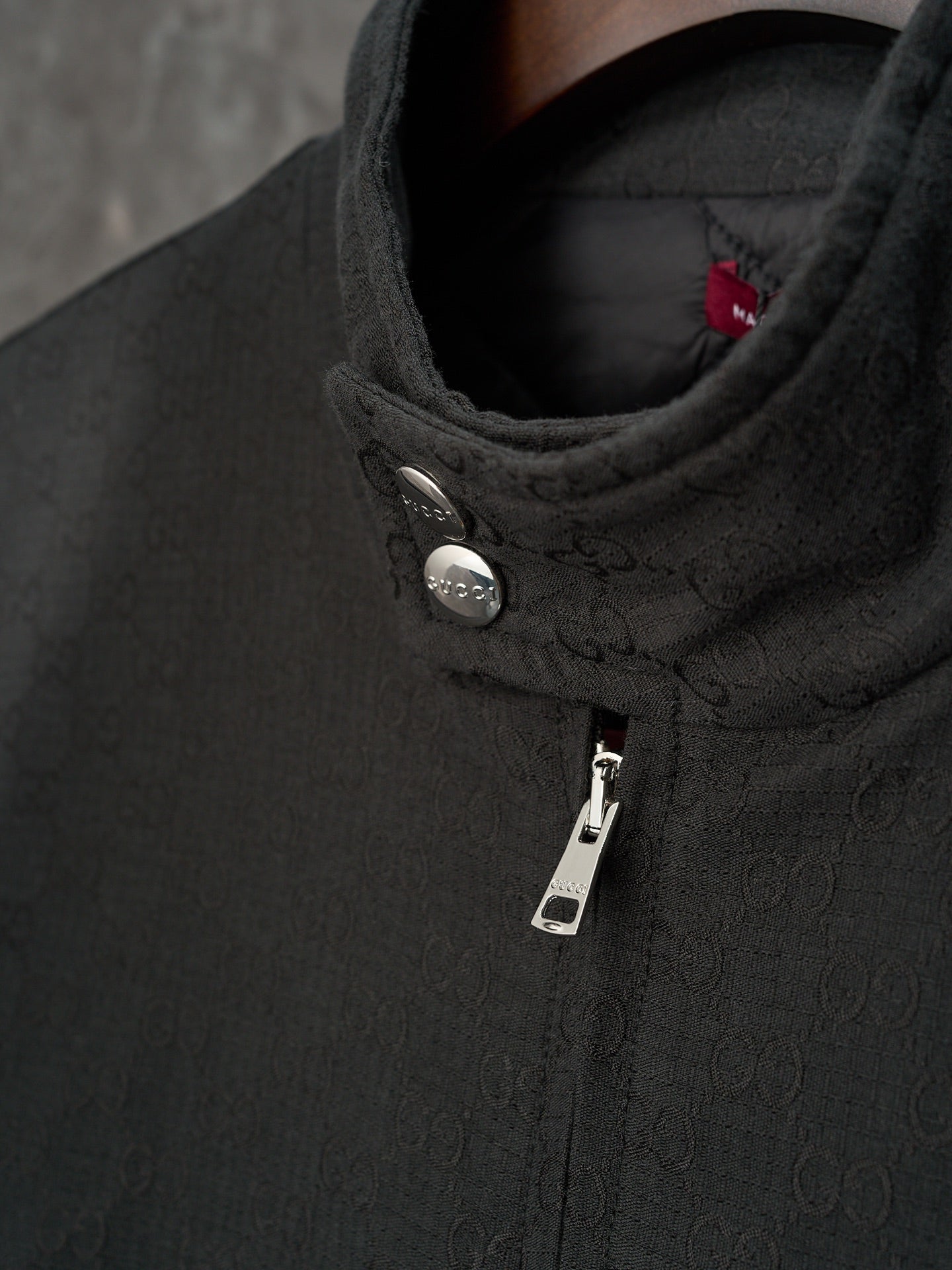 Long jacket collar detail in dark GG pattern with snap button and zipper