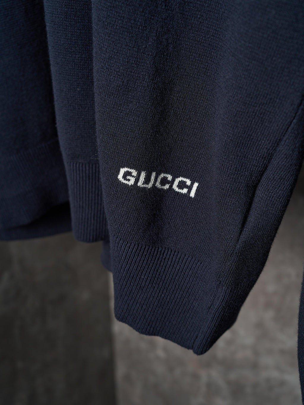 Dark navy knit sweater sleeve cuff with white Gucci logo