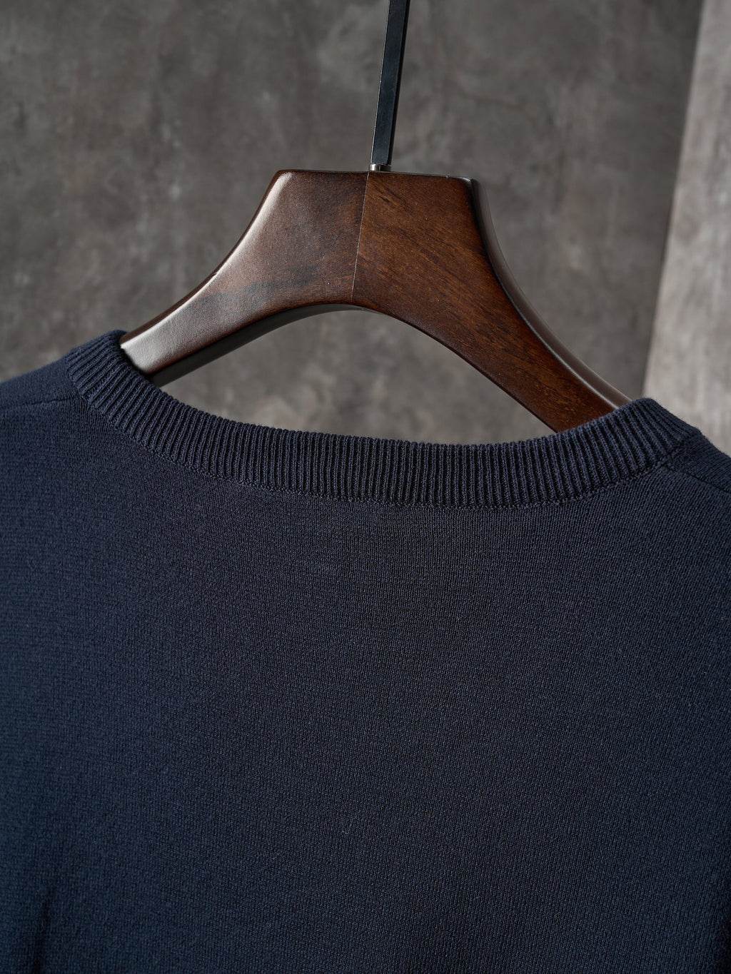 Dark navy knit crewneck sweater neckline with ribbed collar on hanger