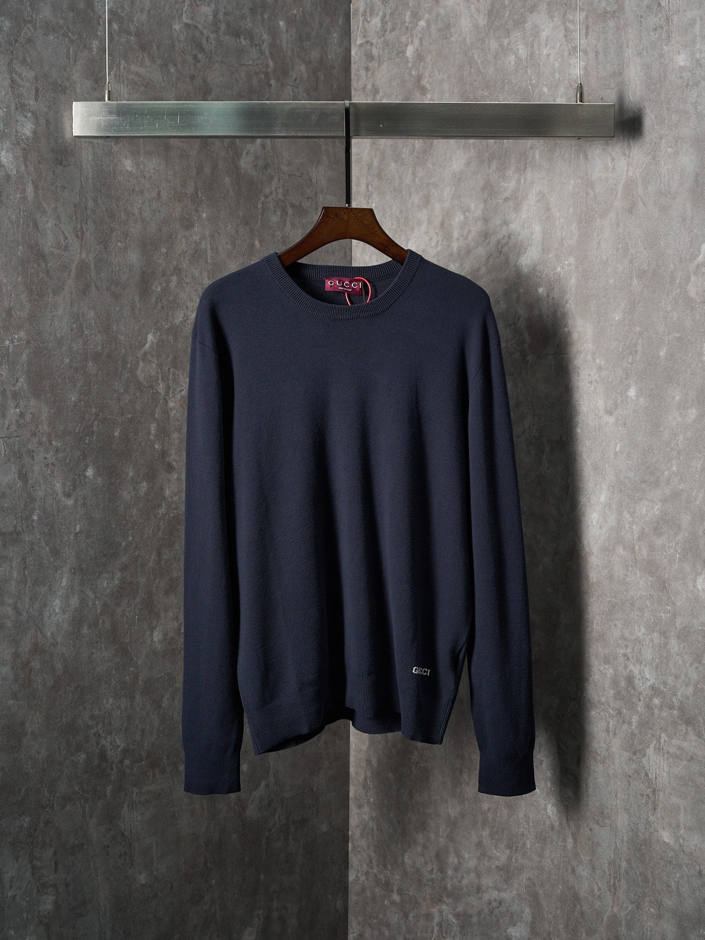 Navy knit long-sleeve sweater with ribbed crew neckline on a hanger