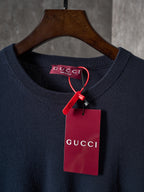 Dark navy knit crewneck sweater with Gucci logo patch and red tag