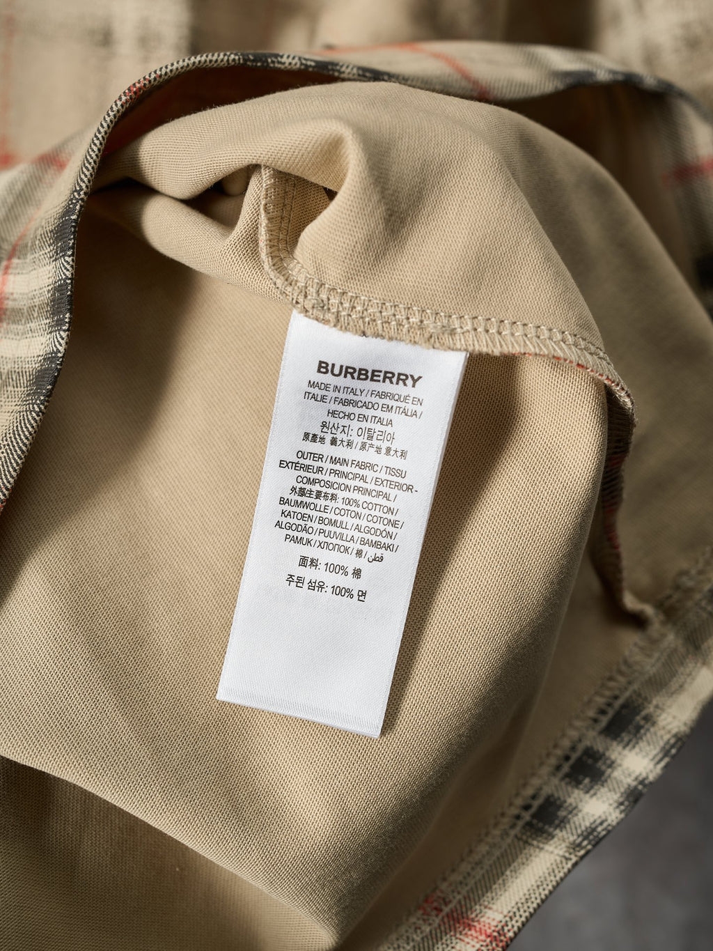 Beige T-shirt interior neck label with Burberry text on a white tag