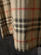 Beige T-shirt fabric detail with black, red, and tan check plaid pattern