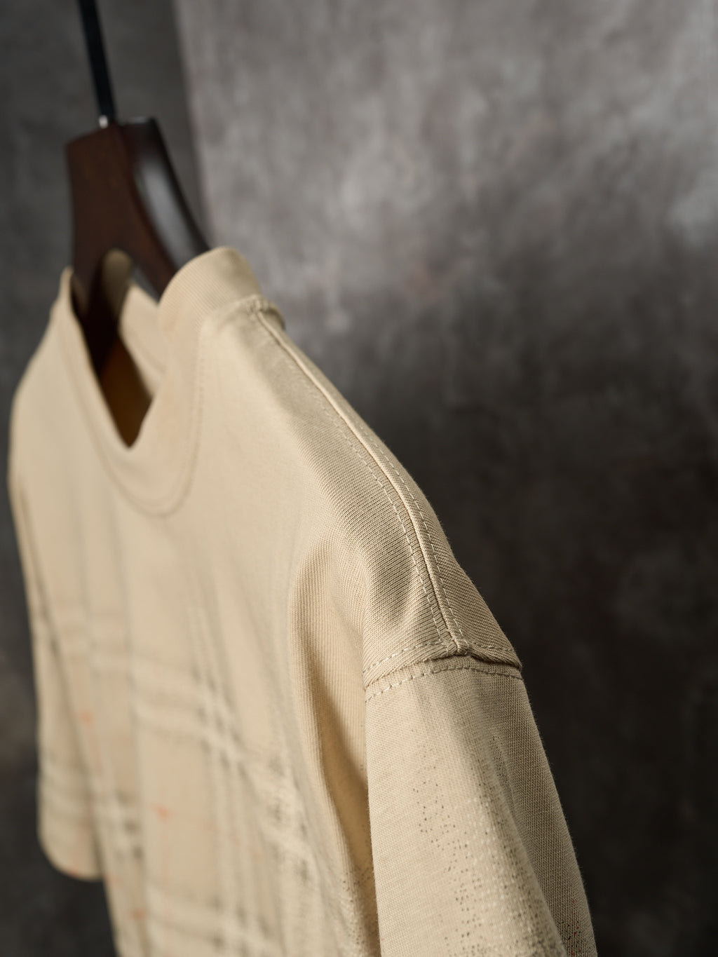 Beige short-sleeve T-shirt side view with subtle check plaid at the lower section