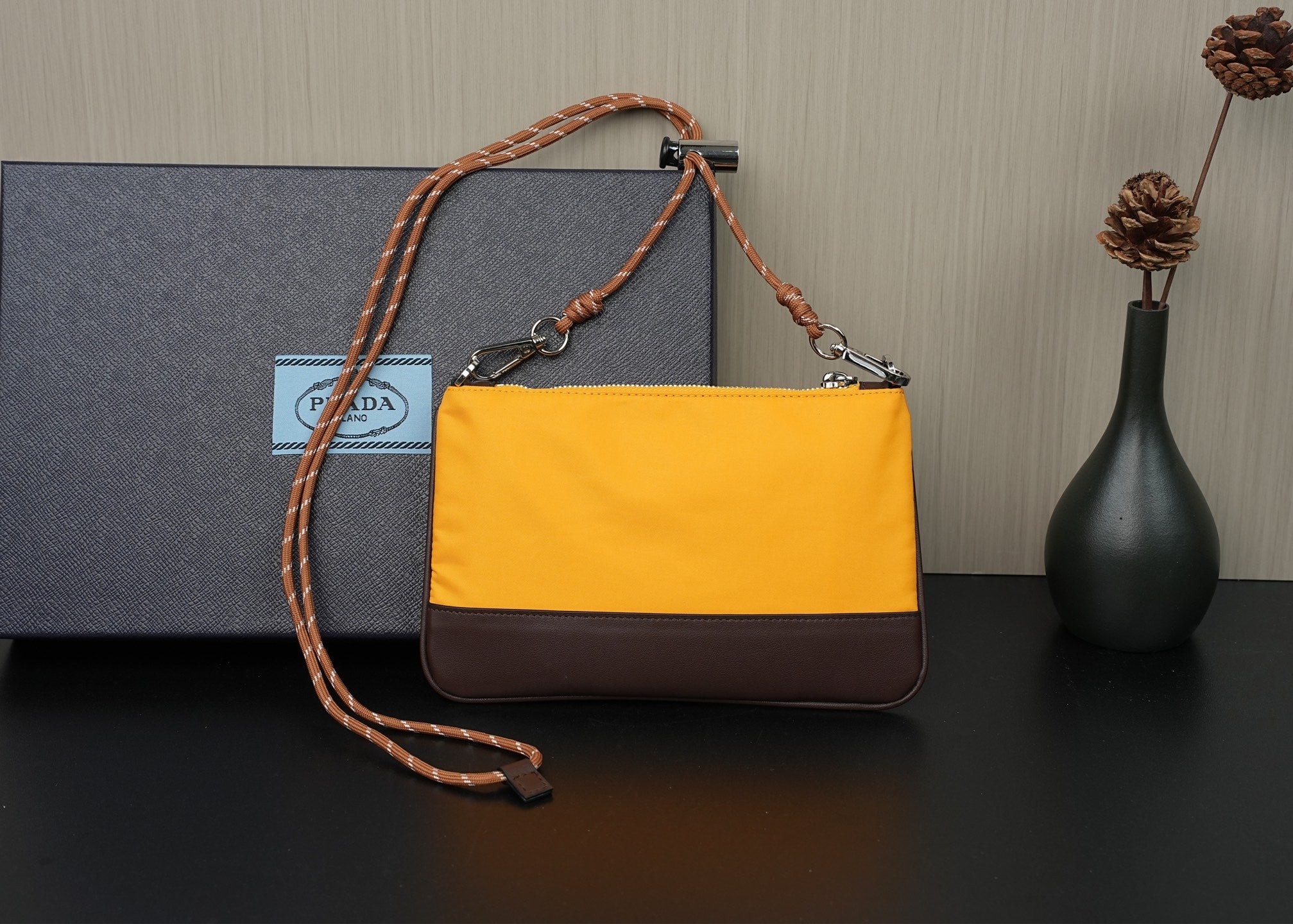 Two-tone shoulder bag with mustard top, brown bottom panel, and braided strap handles