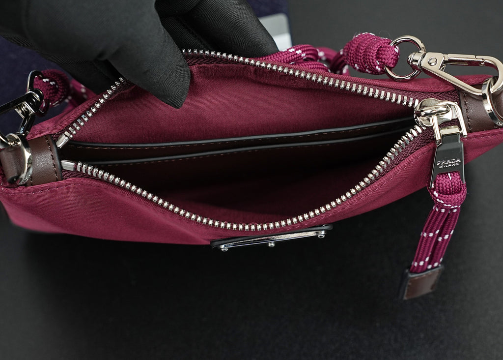 Prada handbag interior view with open zipper, silver zipper teeth, and magenta lining