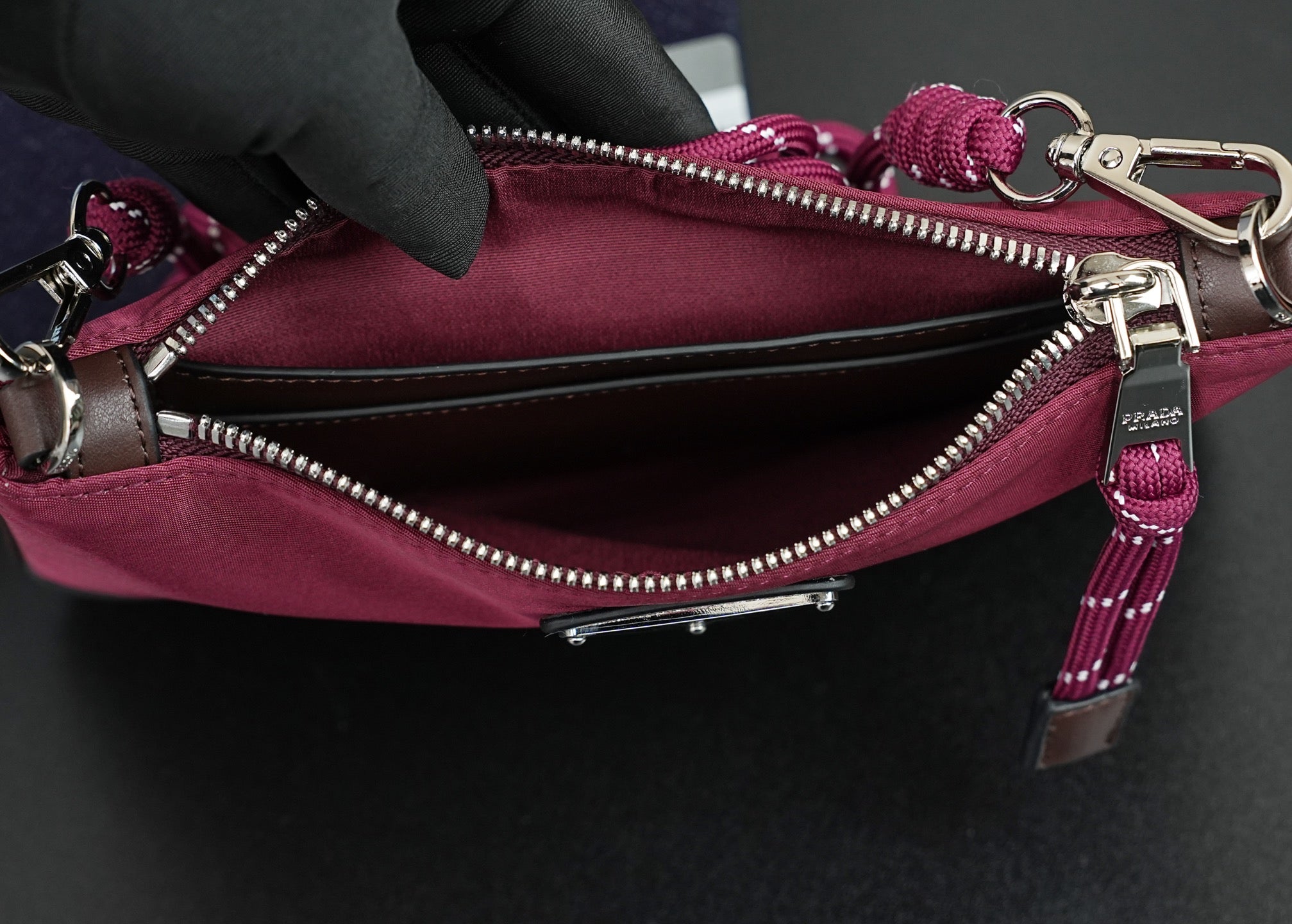 Prada handbag interior view with open zipper, silver zipper teeth, and magenta lining