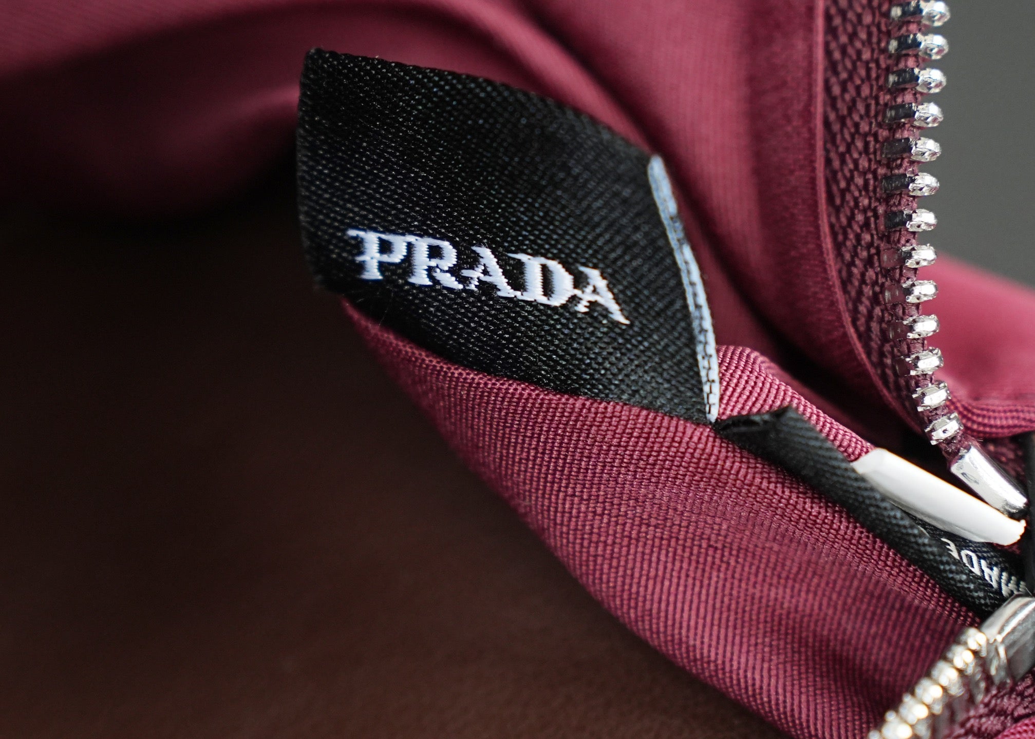 Prada fabric label inside Prada handbag near zipper, on magenta lining