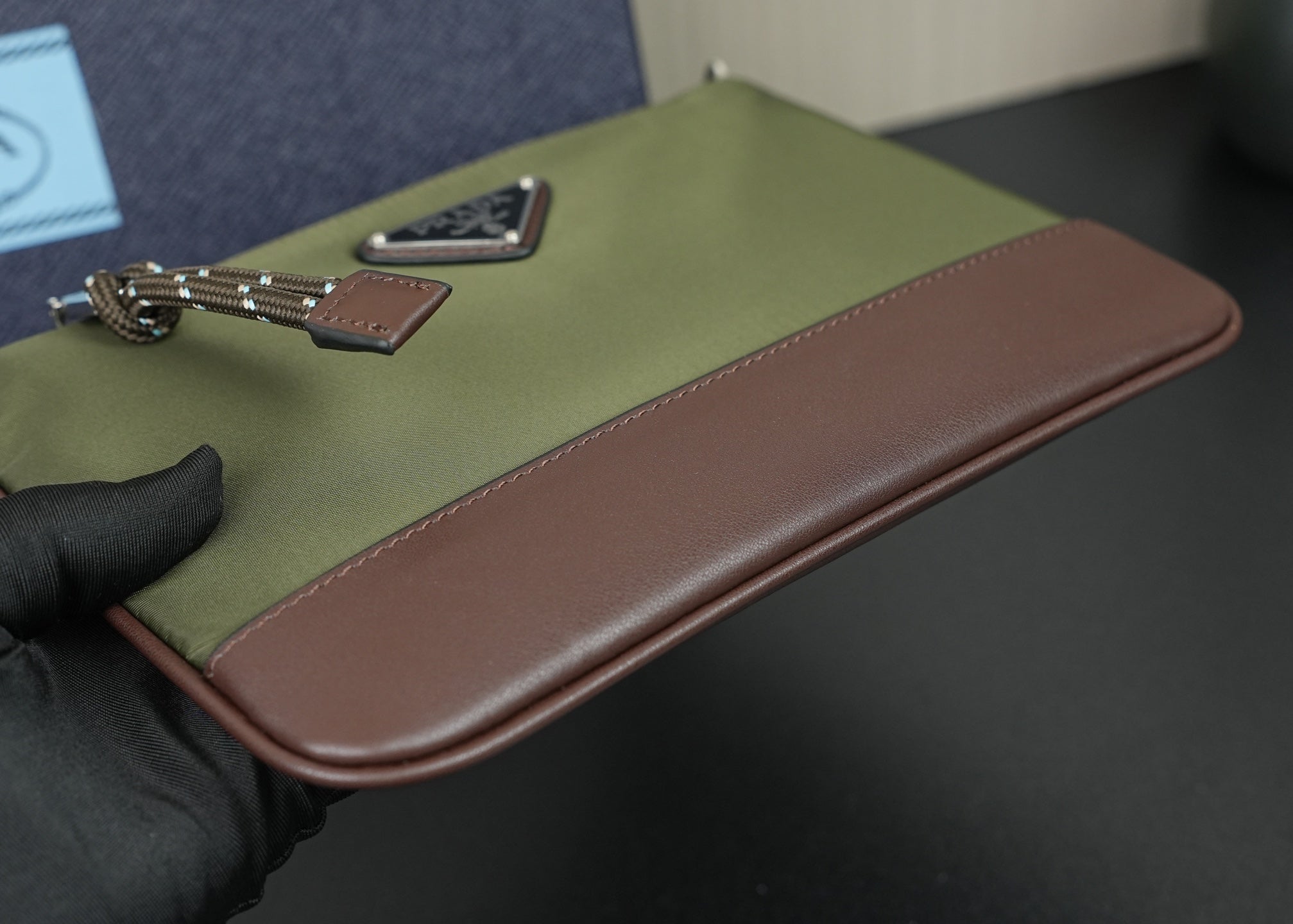 Prada bag close-up of olive flap with brown leather edge and chain hardware