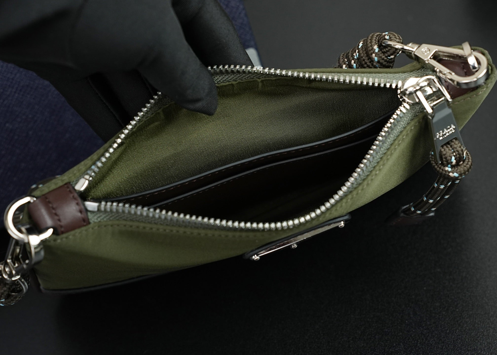 Prada bag interior view with zipper, olive lining, and brown leather tabs