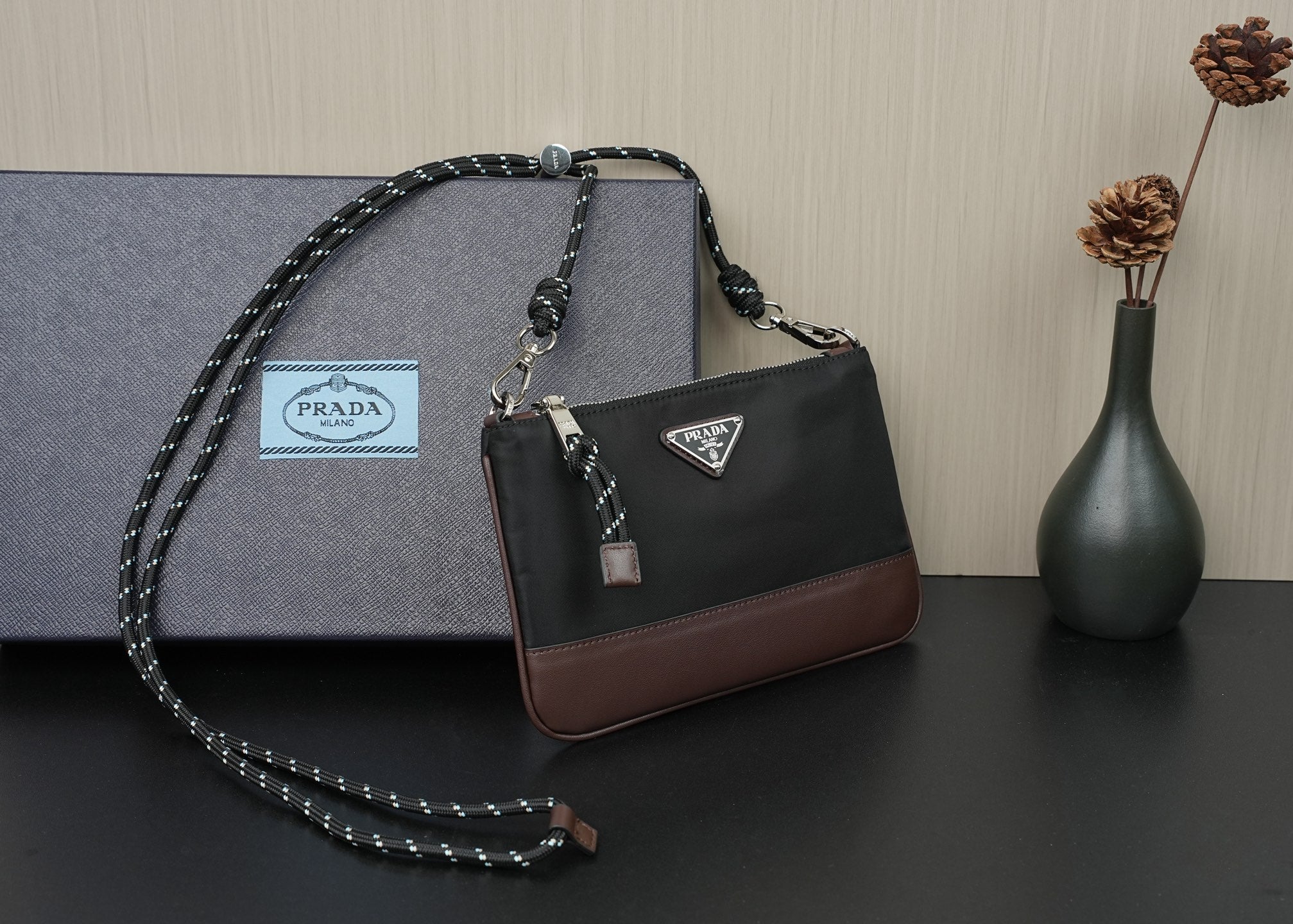 Prada shoulder bag with top handle, black body and brown base trim, chain crossbody strap