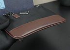 Brown leather trim along edge of black bag with zipper seam and stitched trim