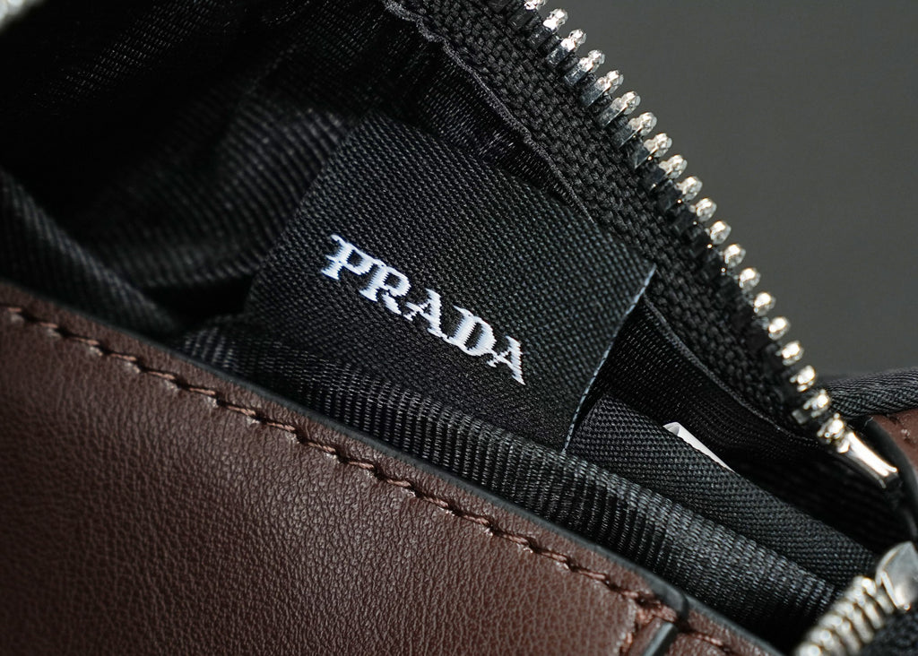 Prada logo label inside black bag lining near zipper track and brown leather trim