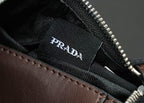 Prada logo label inside black bag lining near zipper track and brown leather trim