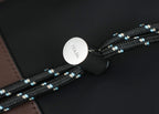 Round Prada snap button on black bag with braided beaded strap and black fabric