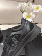 Close-up of black sneaker with Chanel logo, lace eyelets, padded collar, rubber sole