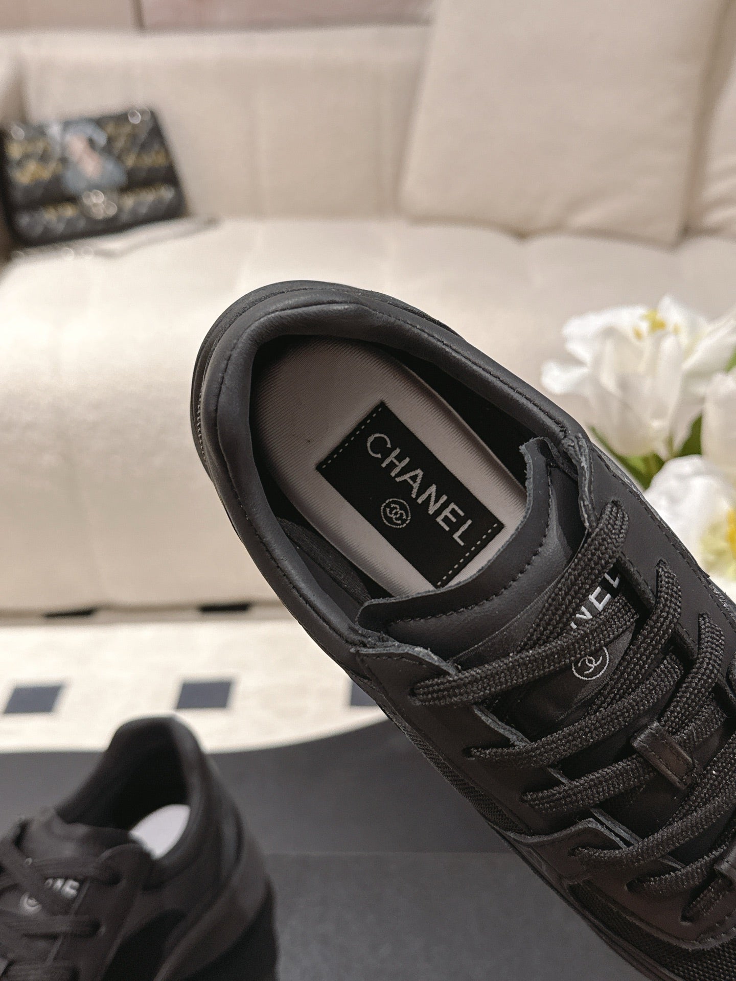 Black lace-up sneaker interior view with Chanel label on insole, cushioned collar