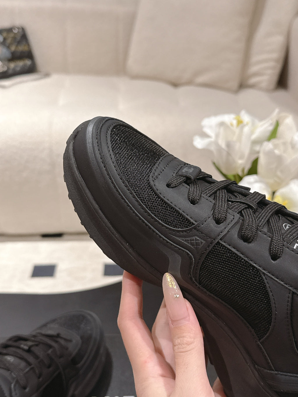 Black sneaker side view with lace-up closure, textured upper, thick rubber sole