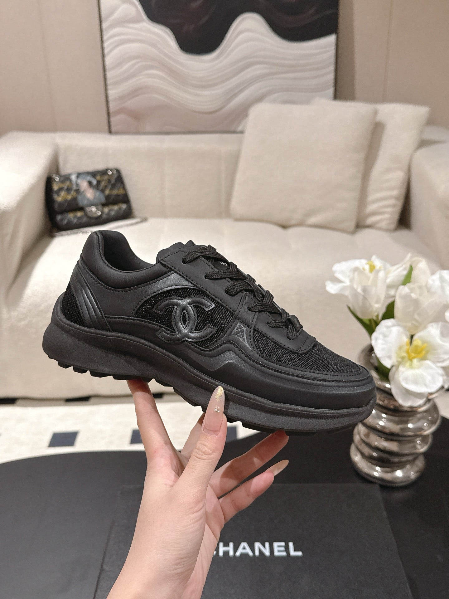 Black lace-up sneaker with Chanel logo on side, stitched panels, thick sole