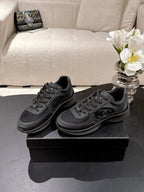 Black lace-up sneakers on box, Chanel logo side detail, textured upper, rubber sole