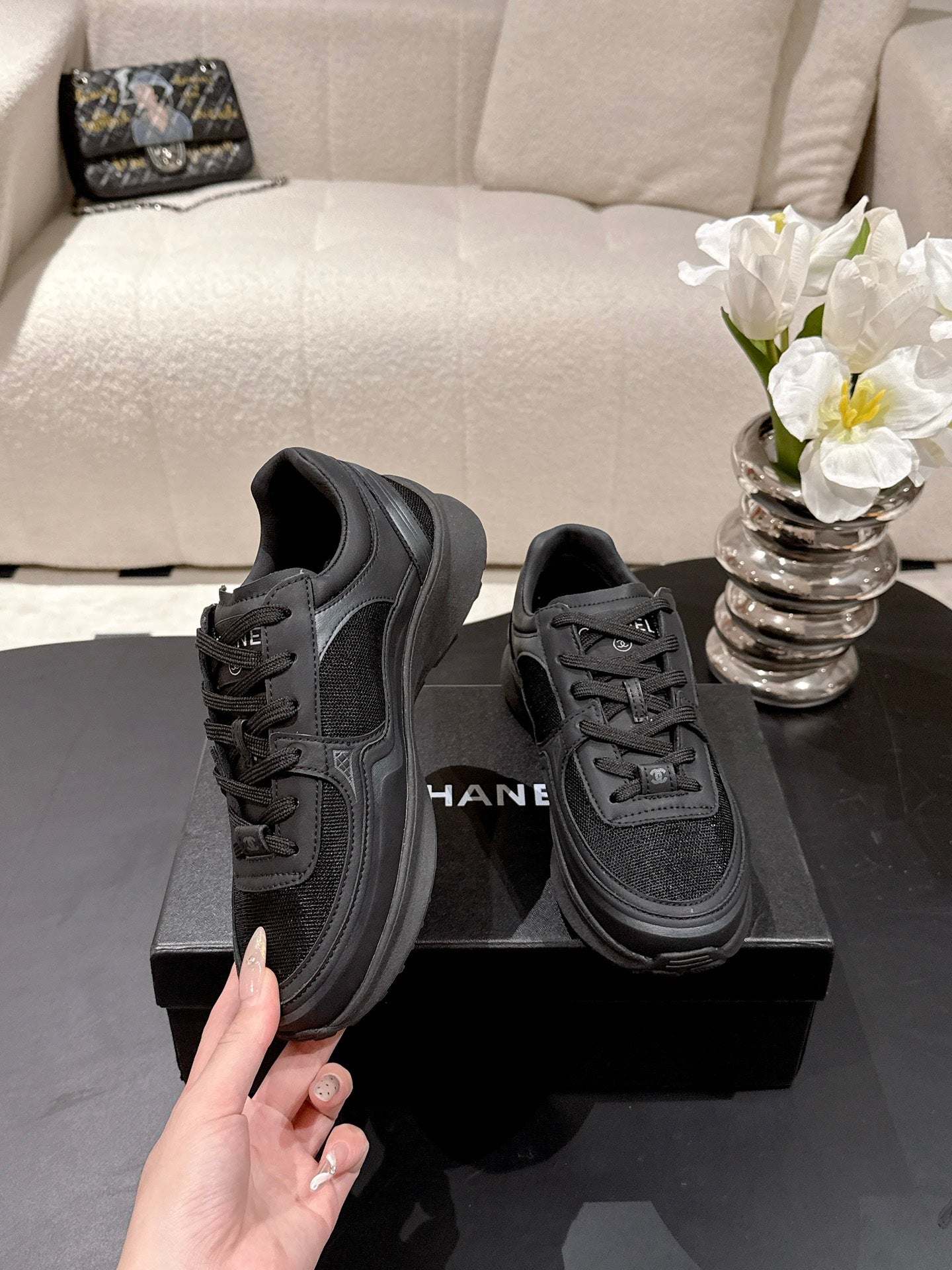 Black lace-up sneakers, Chanel logo on side, chunky tread sole, on display box
