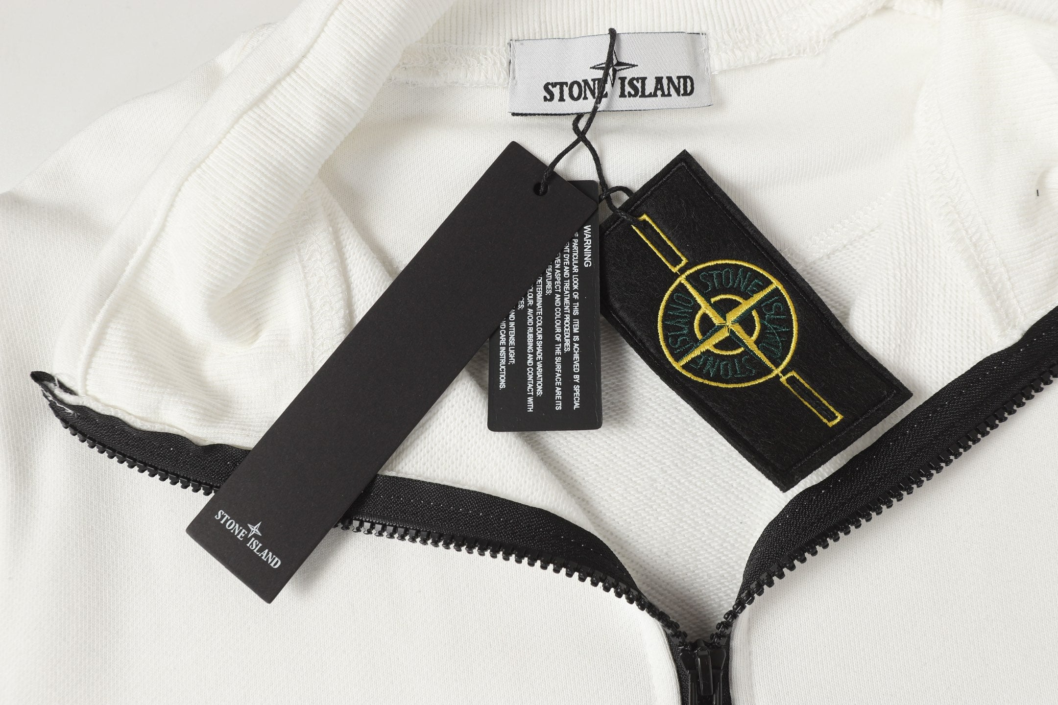 Stone Island quarter-zip fabric close-up with black zipper and branded tags