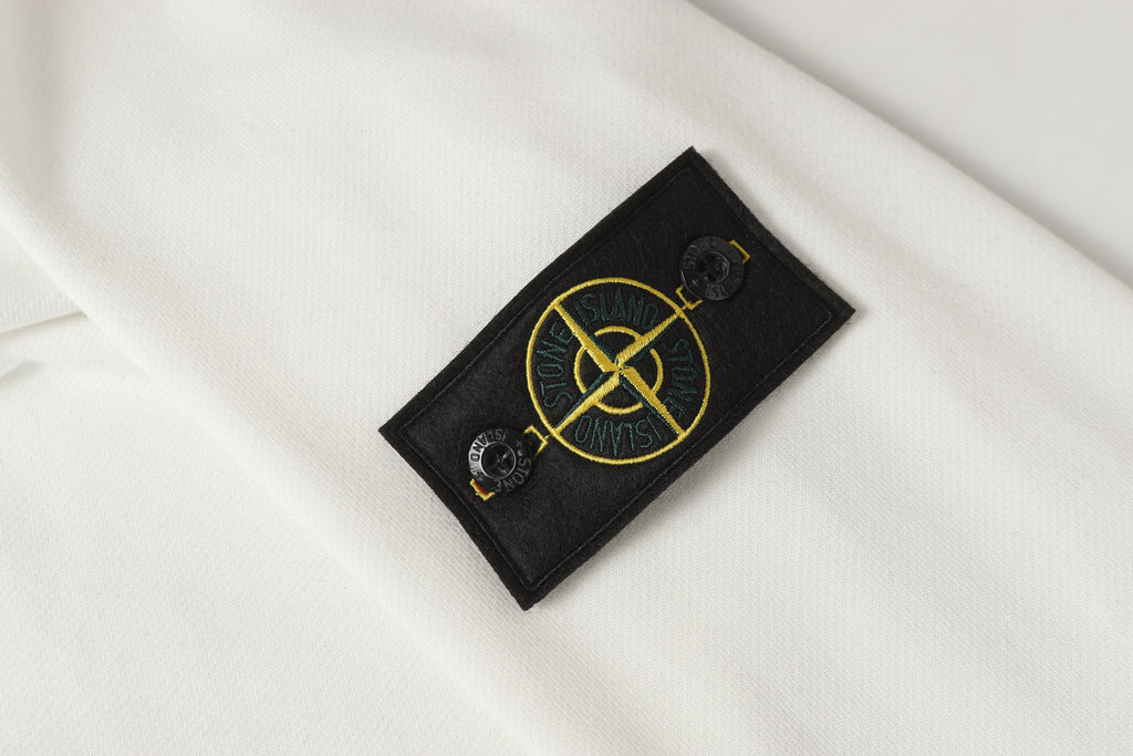 Stone Island sleeve logo patch on white sweatshirt with yellow emblem detail