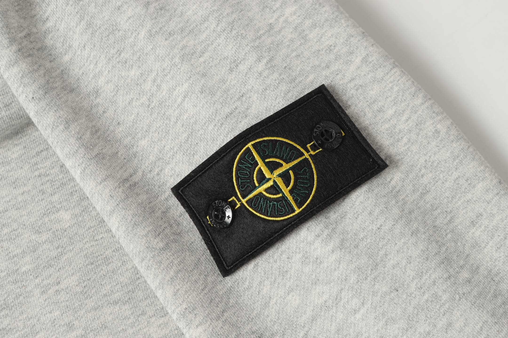 Stone Island logo patch on light gray crewneck sweatshirt chest