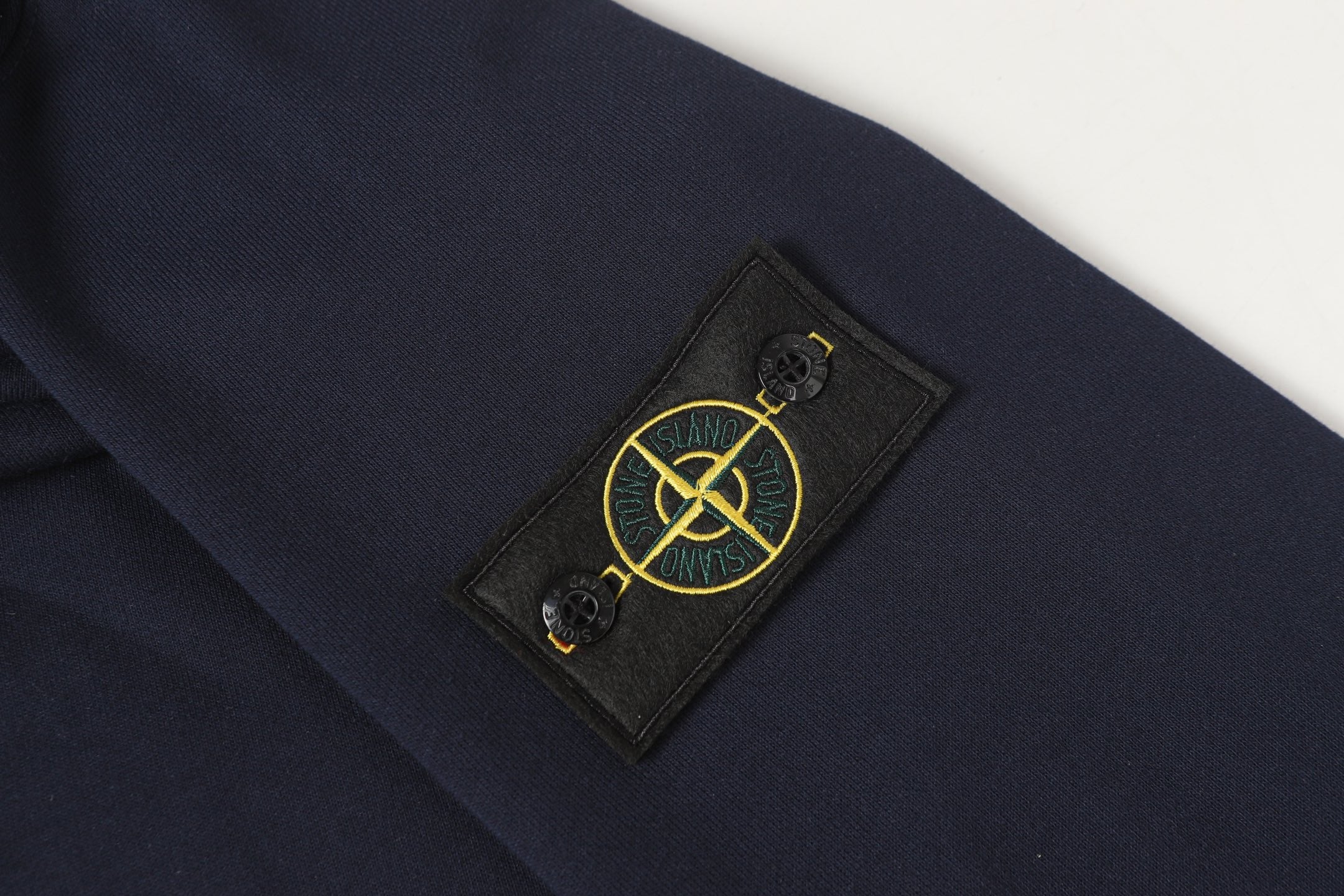 Stone Island logo patch on navy quarter-zip sweatshirt sleeve.