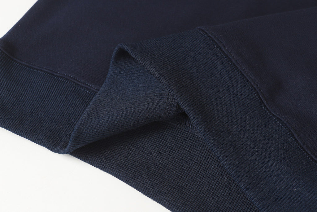 Navy quarter-zip sweatshirt hem with ribbed inner cuff and knit texture.