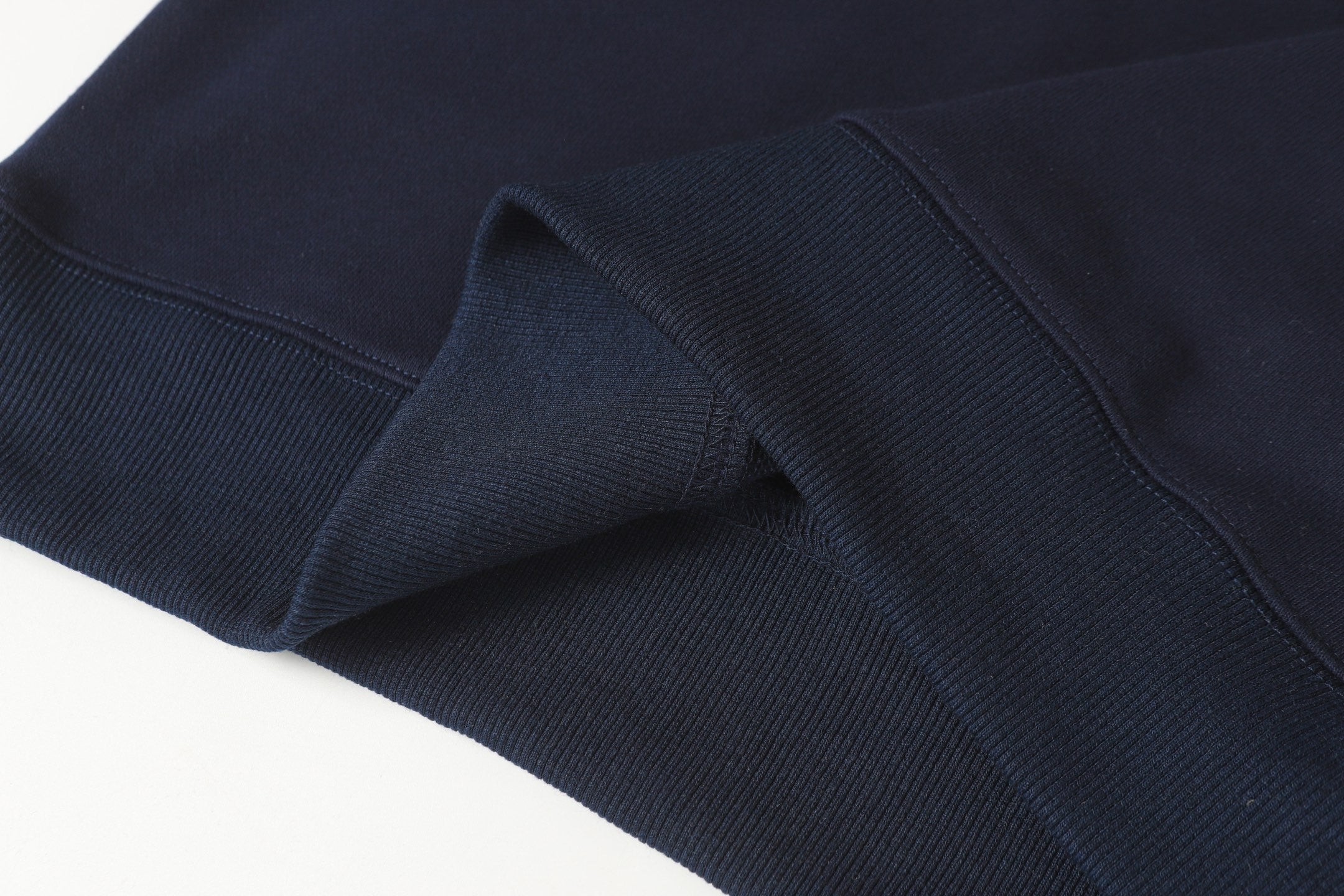 Navy quarter-zip sweatshirt hem with ribbed inner cuff and knit texture.