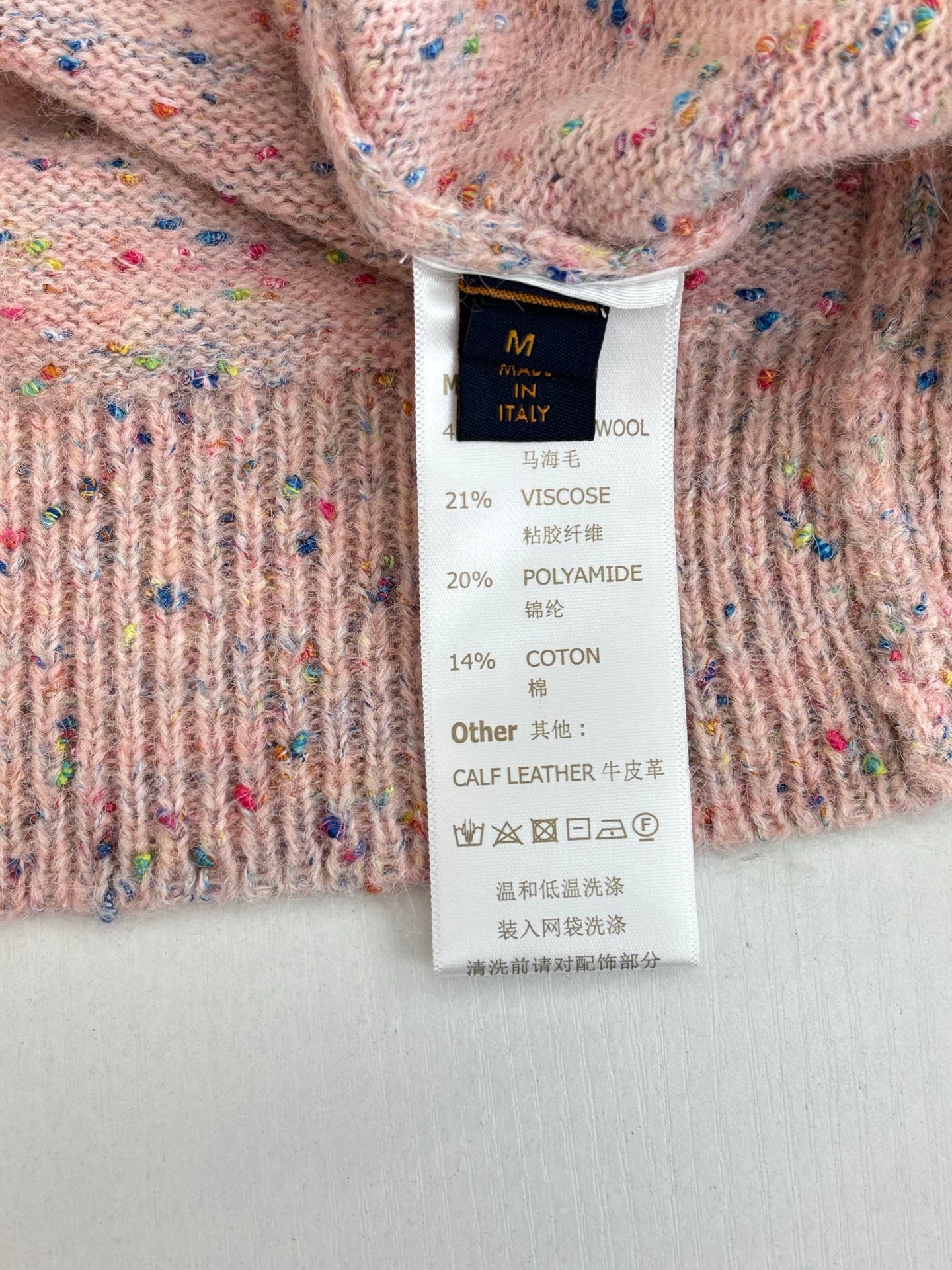 Clothing size and fabric composition label on pink speckled knit cardigan sweater