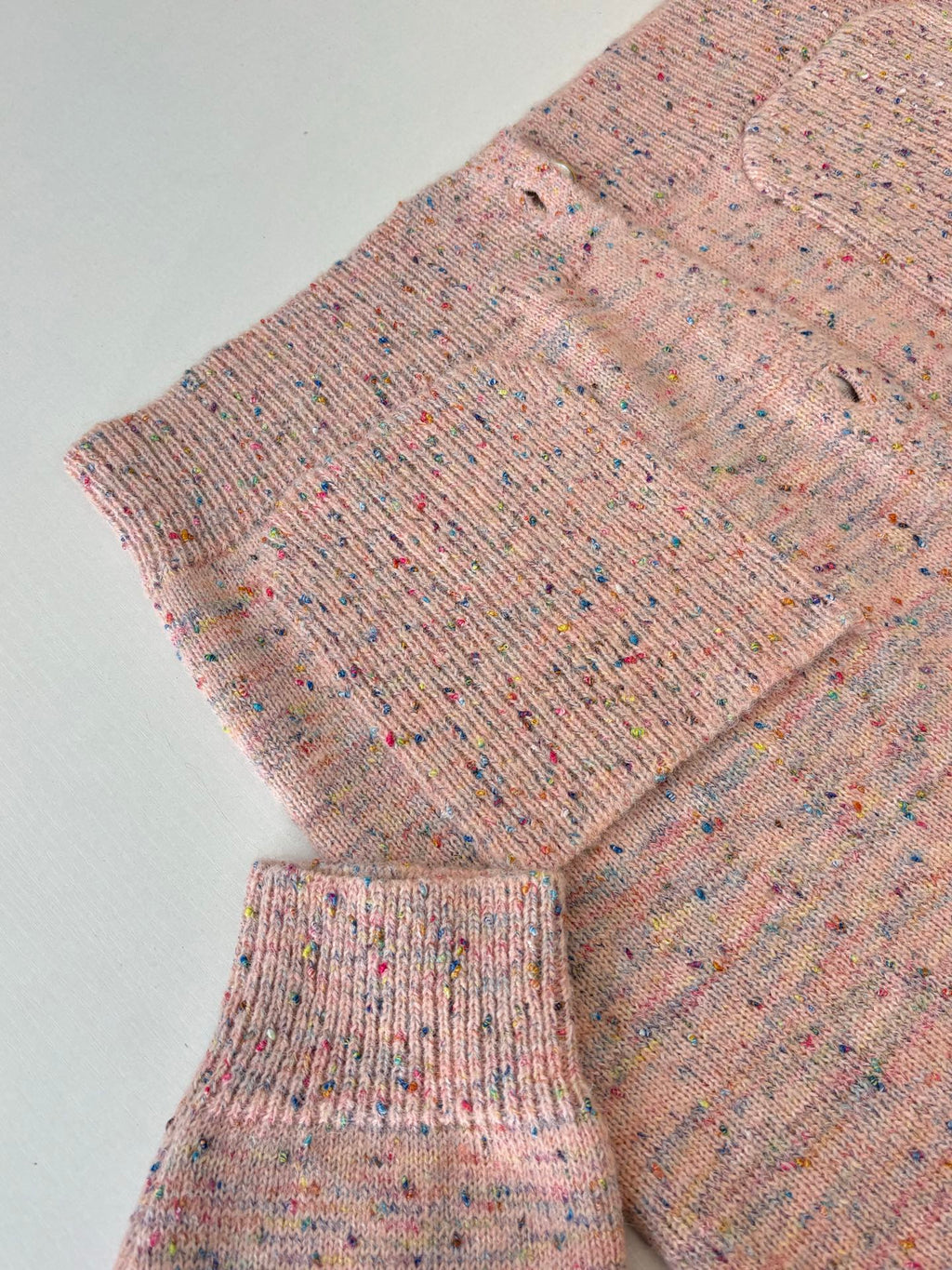Pink speckled knit cardigan sweater sleeve and hem with ribbed cuff and waistband