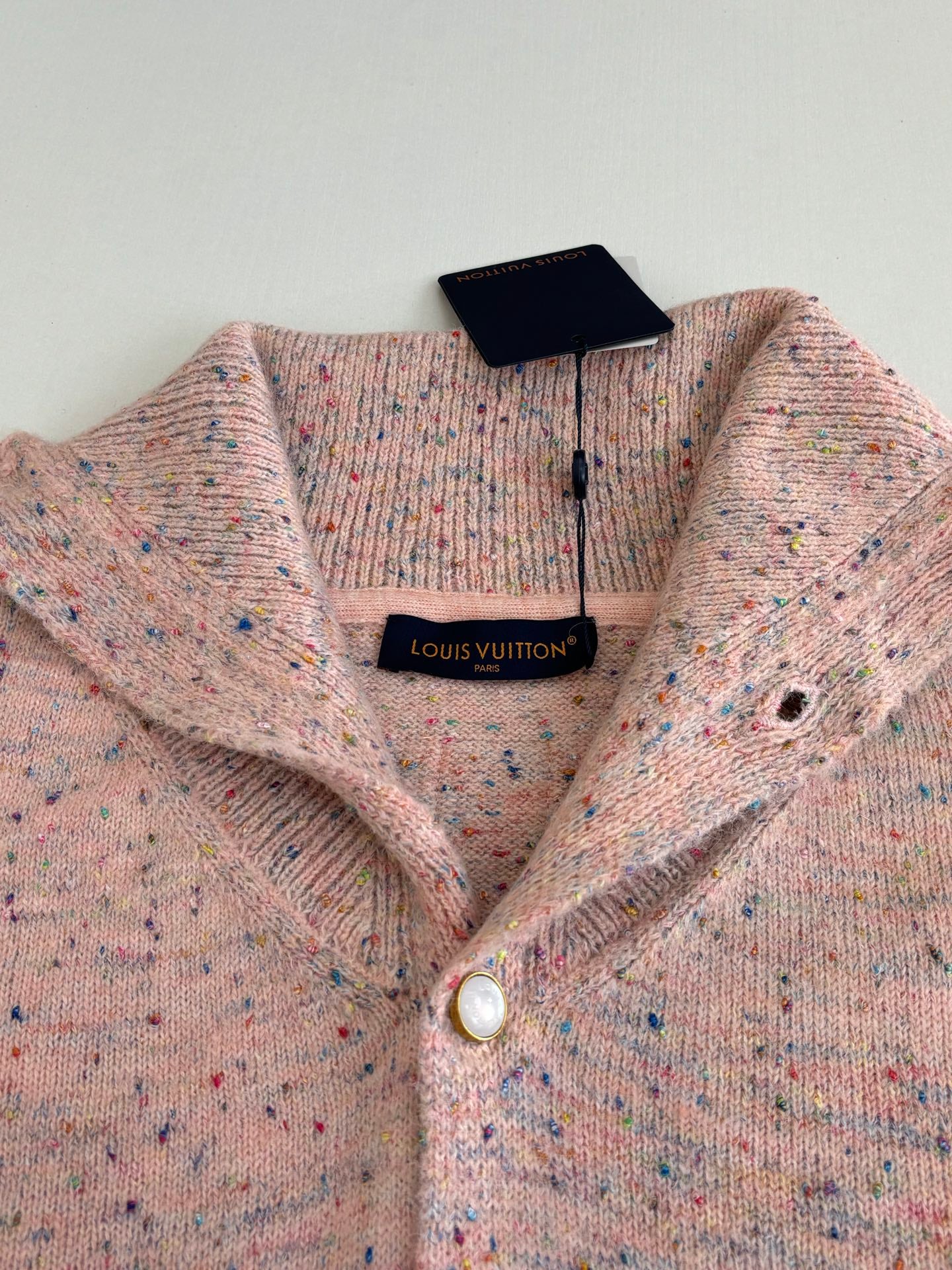 Louis Vuitton knit cardigan close-up with V-neck, pearl button, and neck label