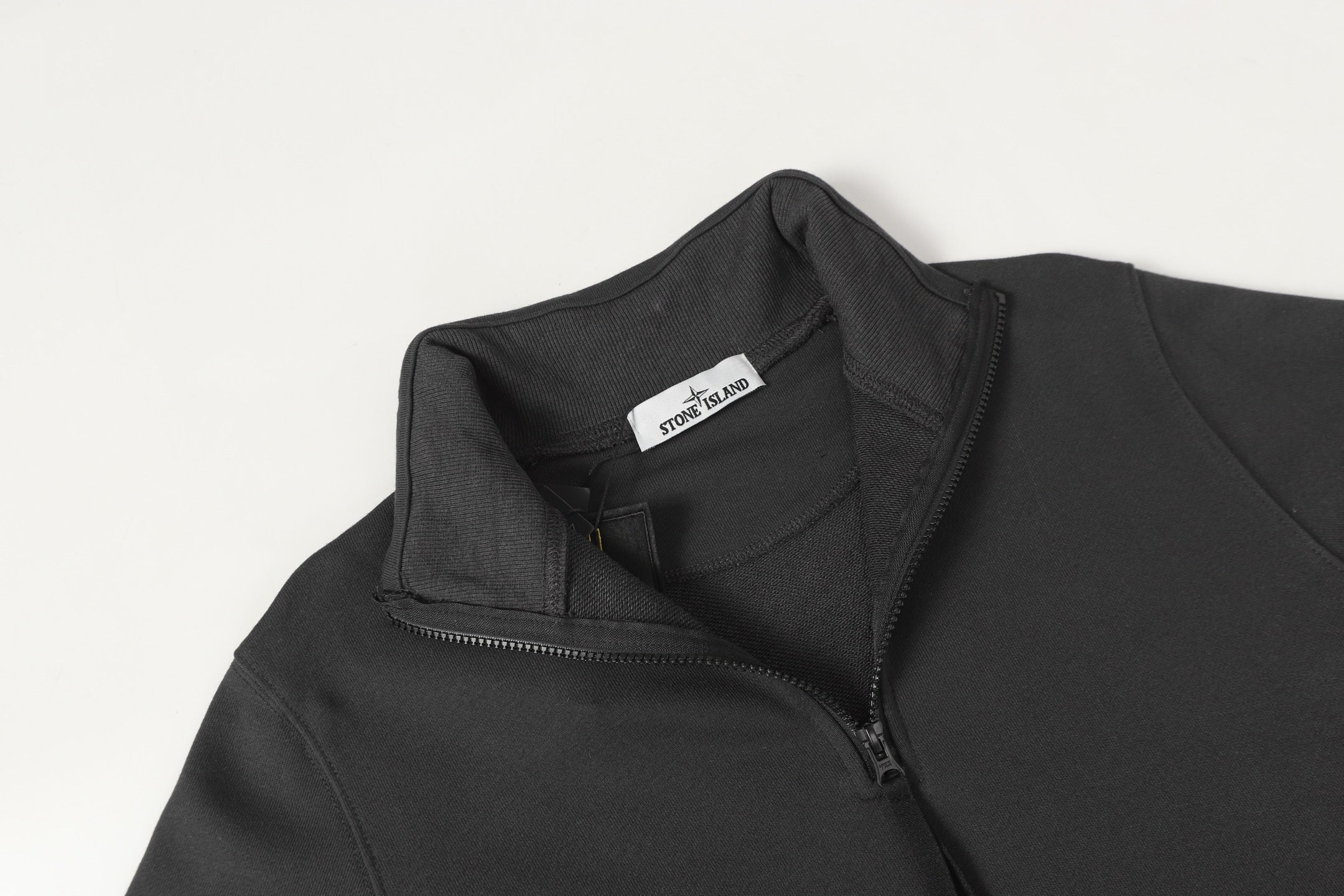 Black half-zip sweatshirt neckline with inner collar label, shoulder close-up