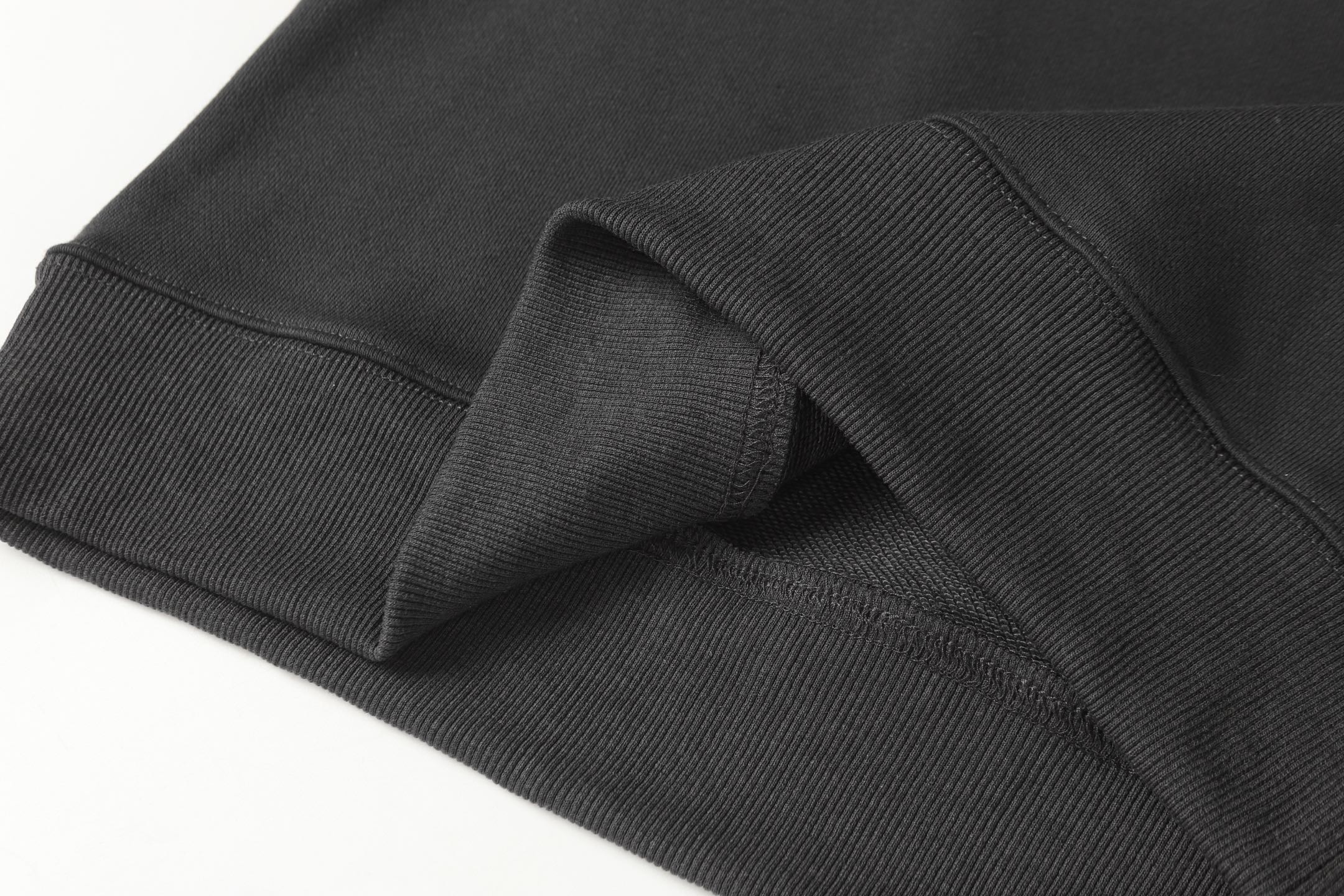 Black ribbed waistband detail on half-zip sweatshirt, folded close-up