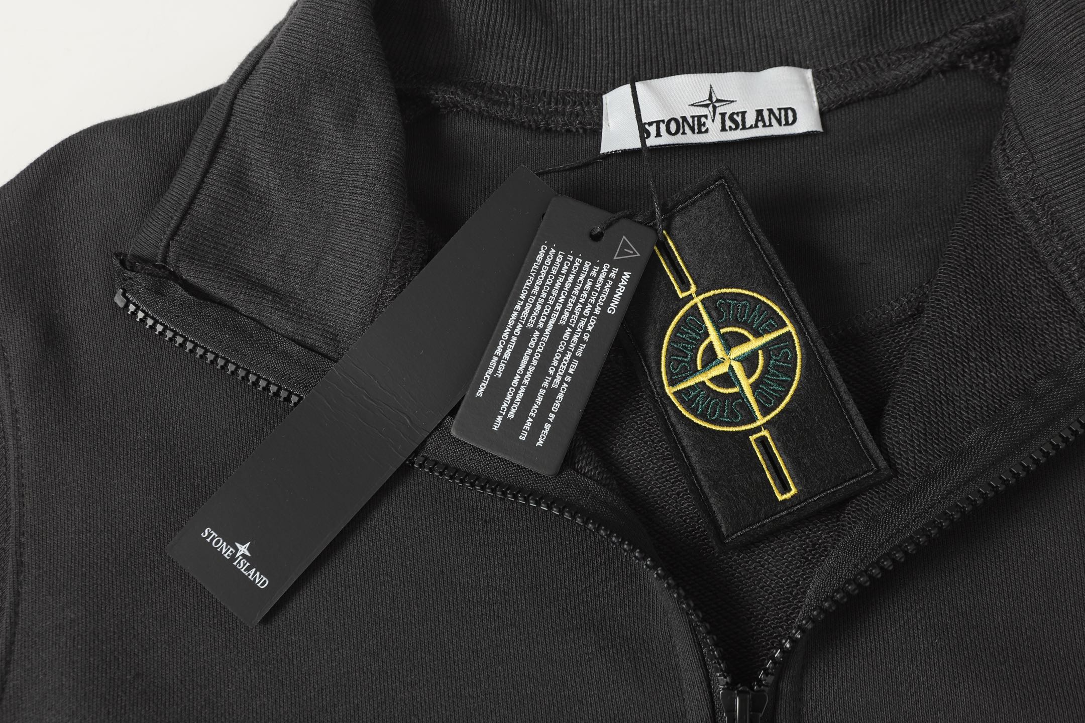 Black half-zip sweatshirt close-up with zipper pull and interior brand label