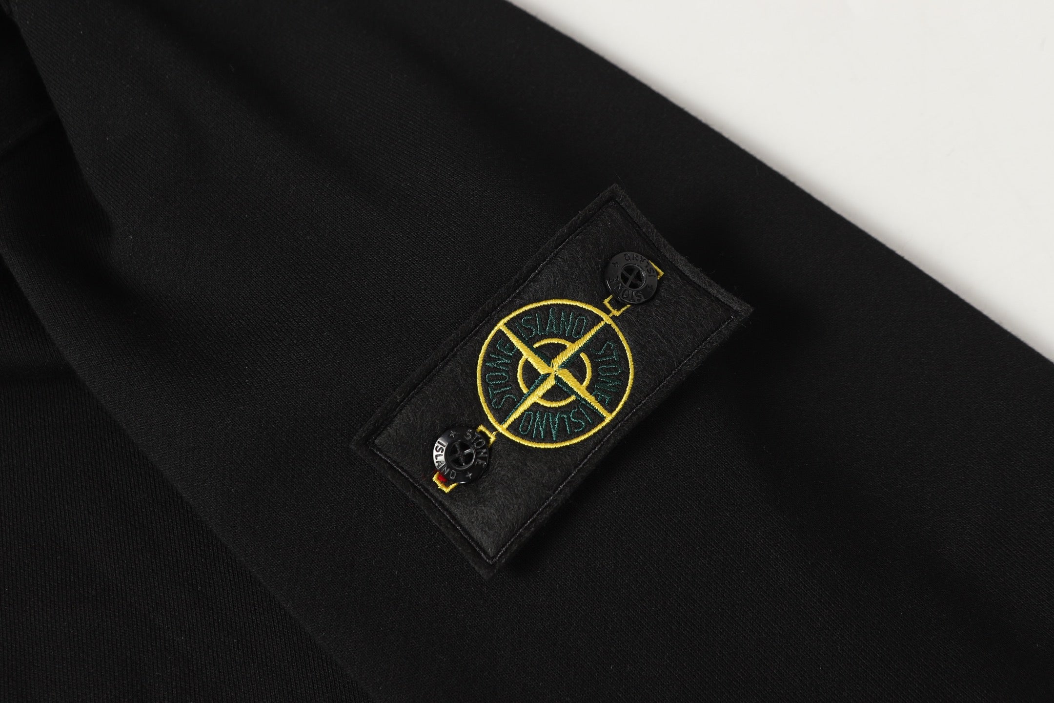 Black sweatshirt with yellow embroidered Island logo patch on sleeve