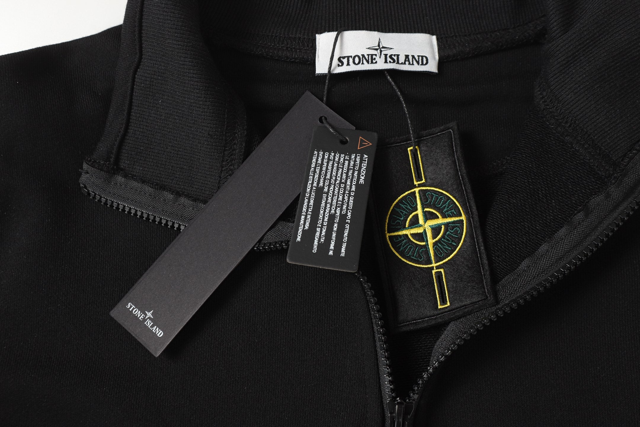 Black quarter-zip top with metal zipper pull, neck label, and care tag
