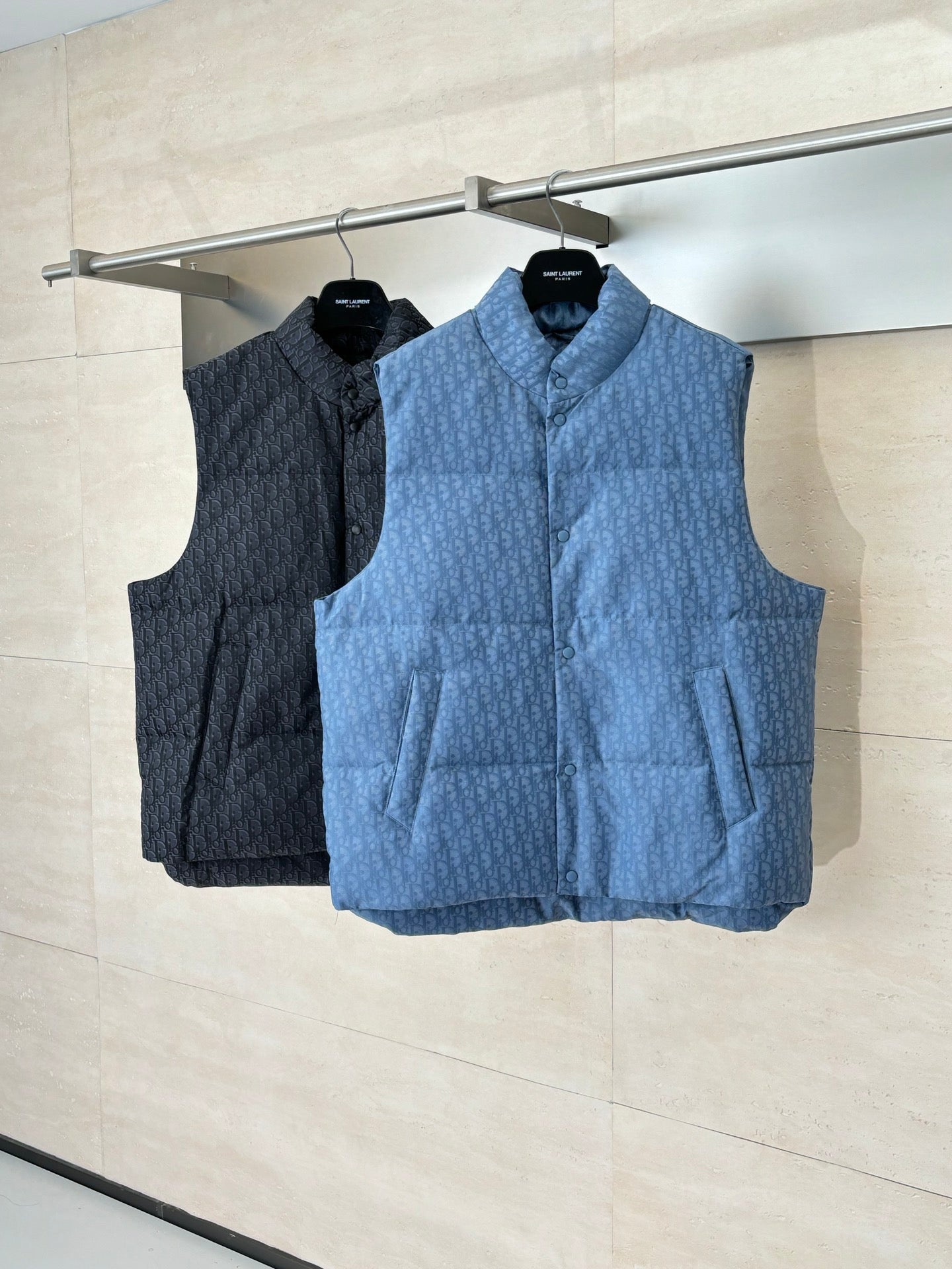 Two sleeveless padded vests on hangers: dark and light blue, with stand collars