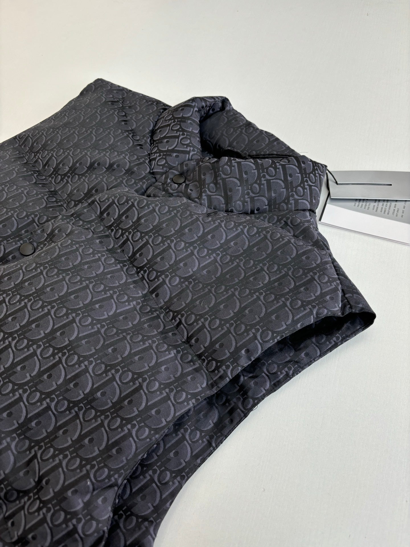 Folded sleeveless quilted vest in dark Dior monogram fabric with stand collar.