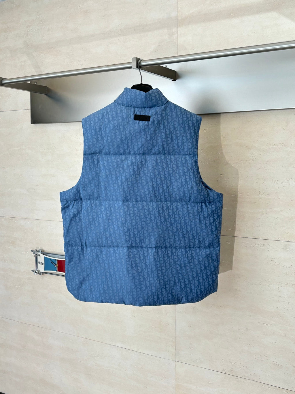 Blue sleeveless padded vest with stand collar, visible front yoke and button placket