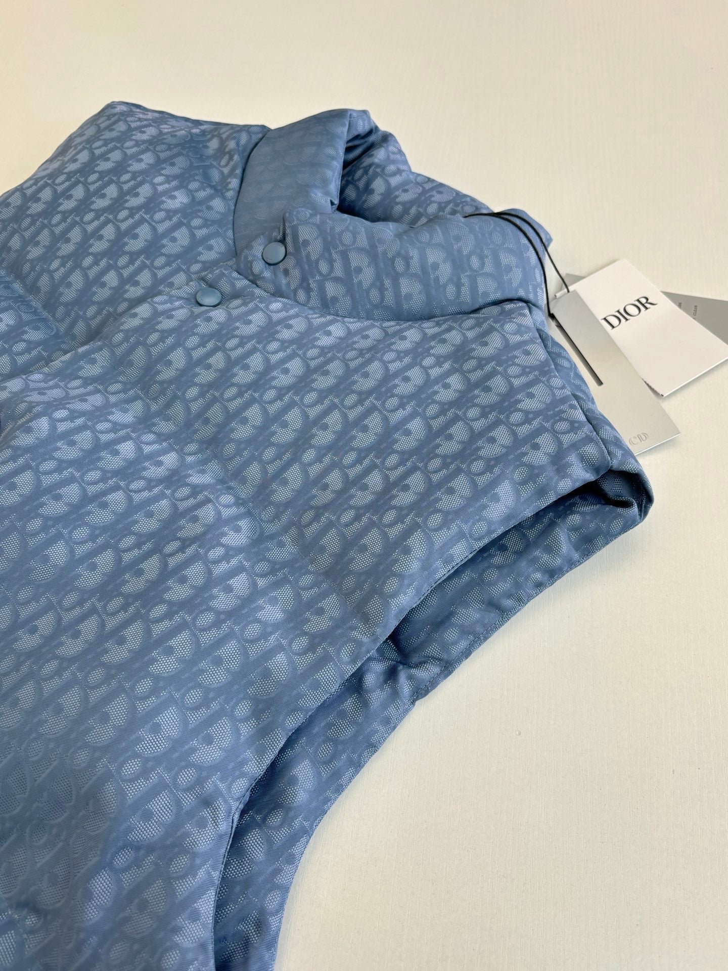 Folded light blue sleeveless vest with Dior-style monogram pattern, collar and snap