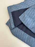 Light blue sleeveless vest with monogram pattern and dark interior panel with snap