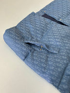 Light blue sleeveless vest with allover monogram pattern, front snaps and curved yoke