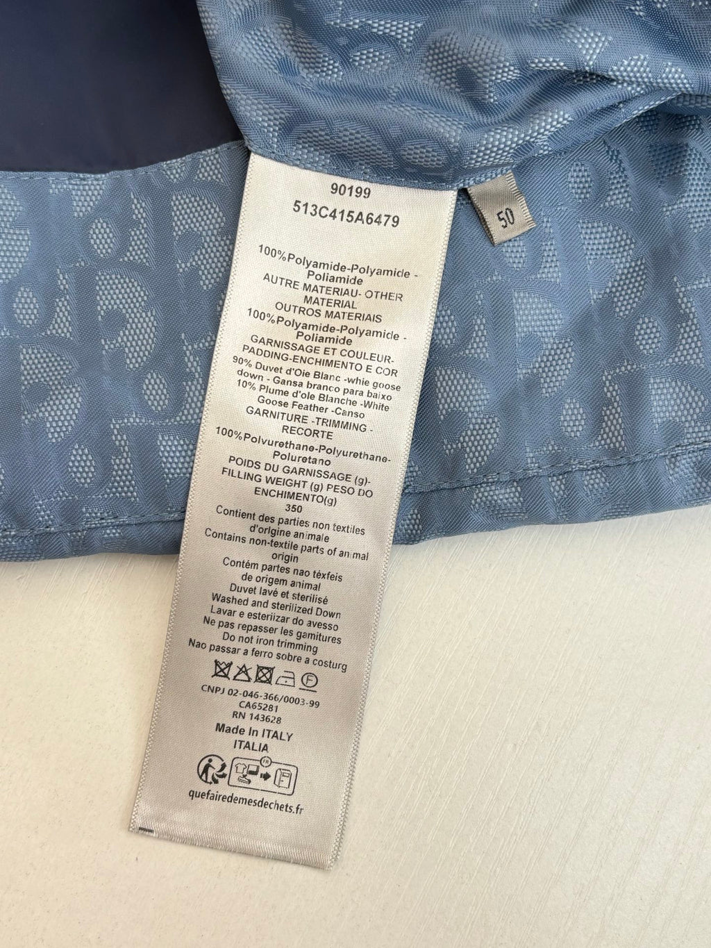Care label and size tag on blue monogram fabric of a sleeveless vest