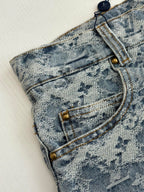 Close-up of blue monogram denim shorts: belt loops and stitched fly