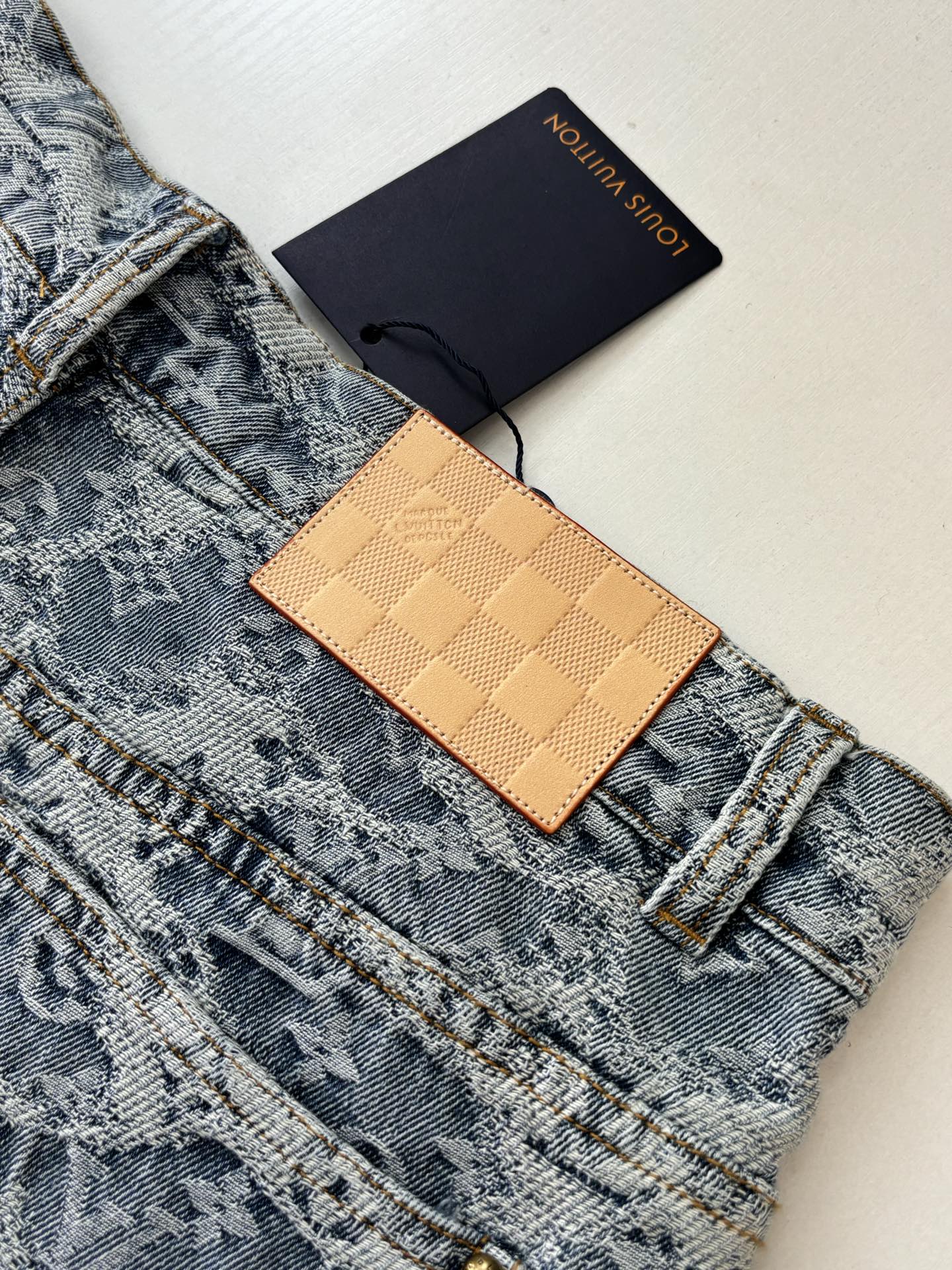 Blue monogram denim shorts with tan leather tag and gold-tone buttons