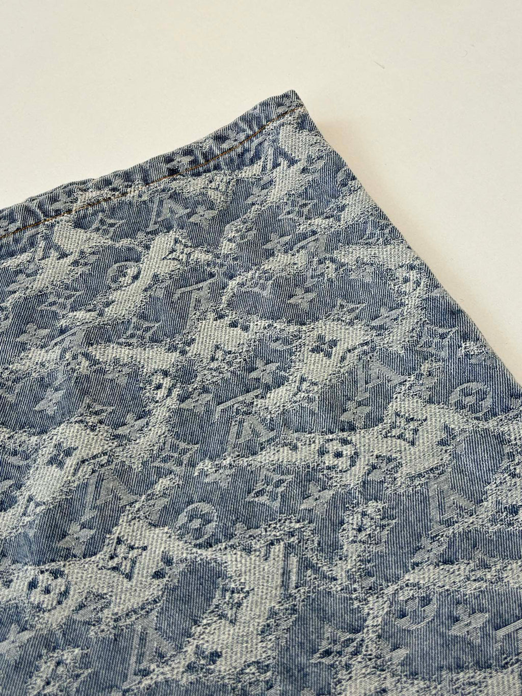 Close-up of blue monogram denim shorts side panel with stitched seam